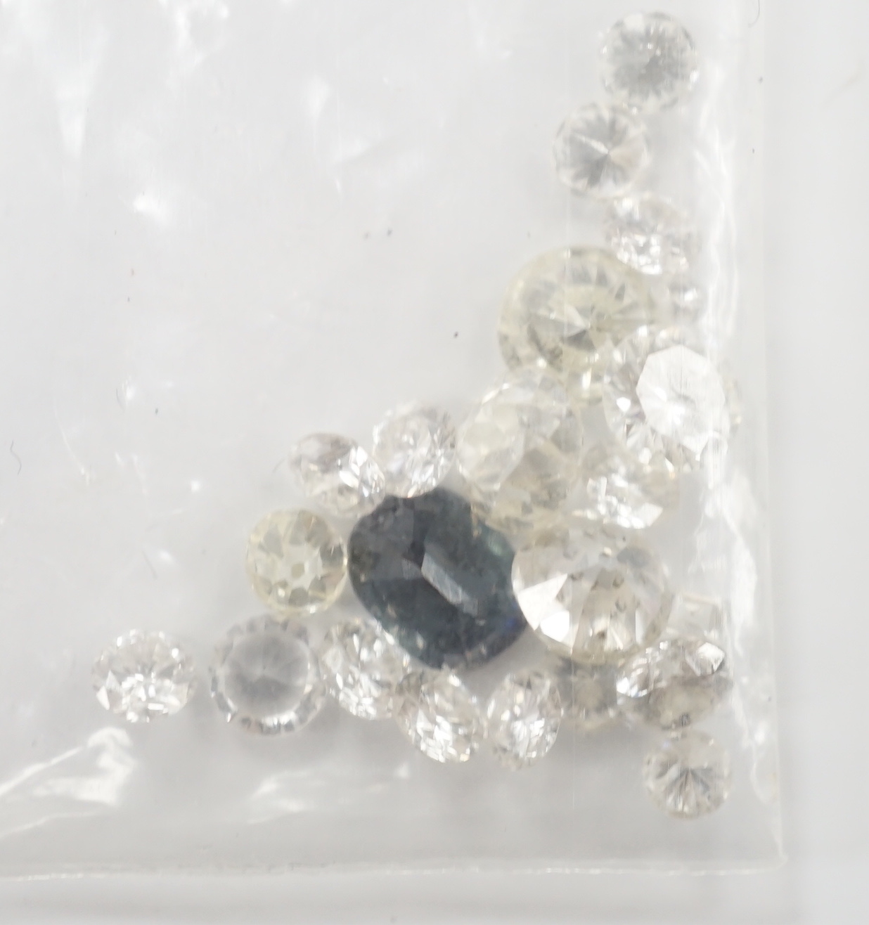 Twenty one unmounted cut diamonds, the four largest stones with an approximate total weight of 2.30ct, together with one unmounted cut sapphire.